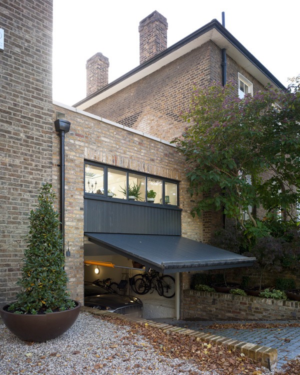 A London stock brick garage and house extension with a gravel drive edged in brick