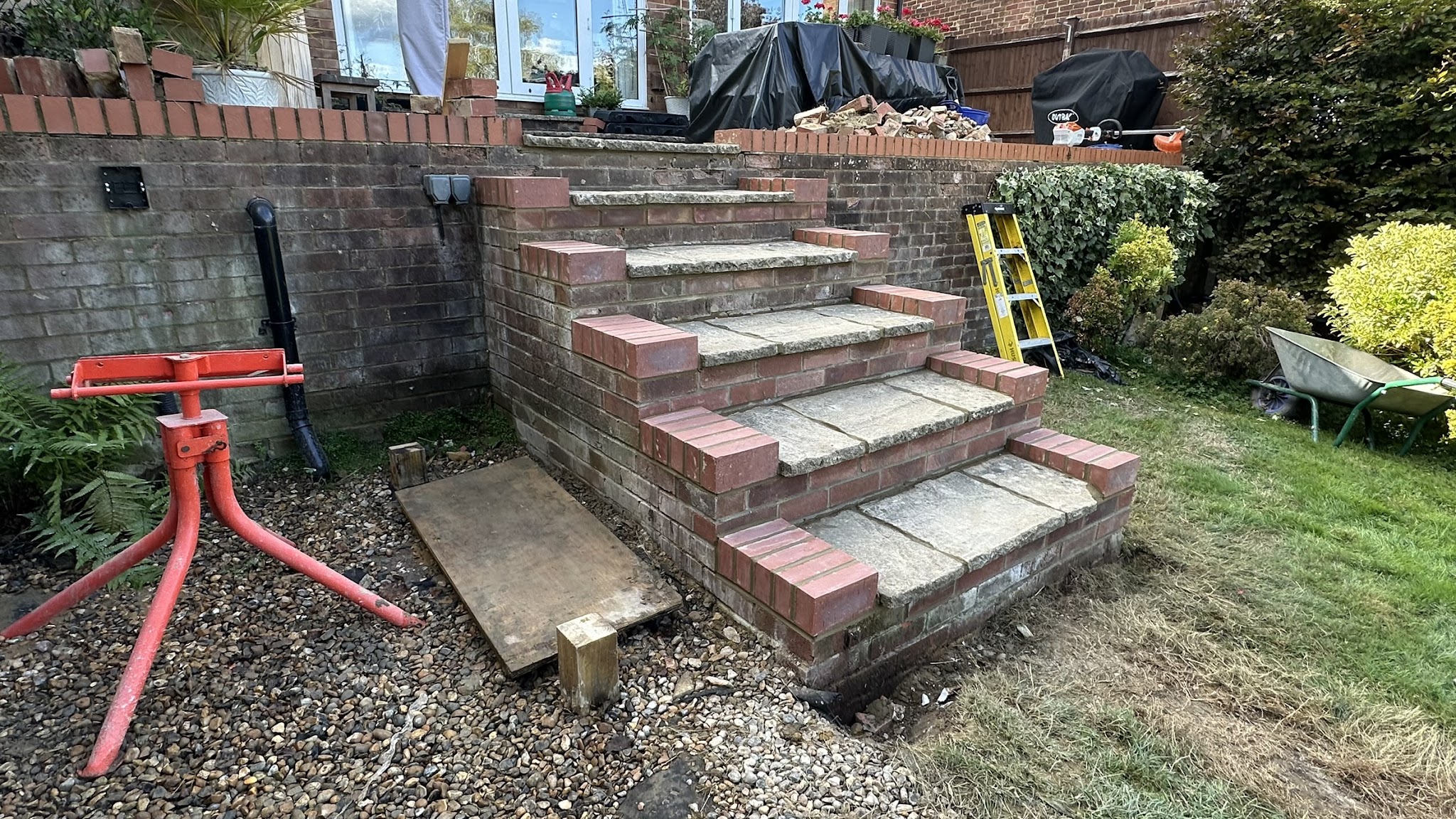 Red brick garden steps with slab treads being built, tools on site