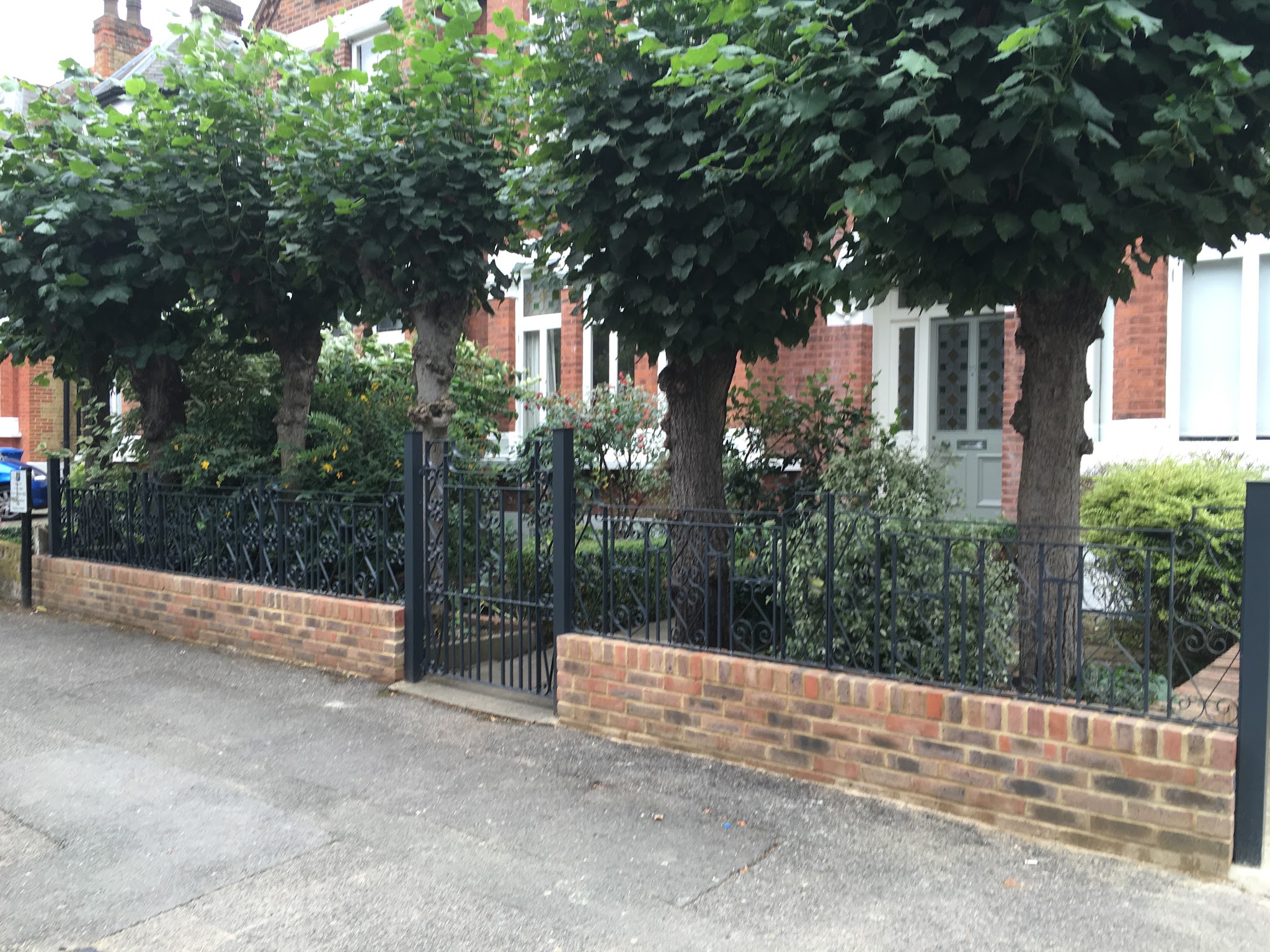 Red brick front garden wall with iron railings and a gate
