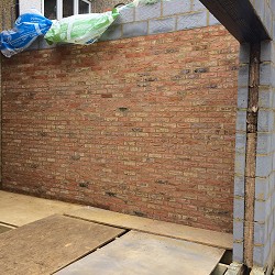 New facing brick laid over blockwork on an extension wall