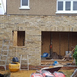 A stock brick rear extension in progress with openings for doors and a window